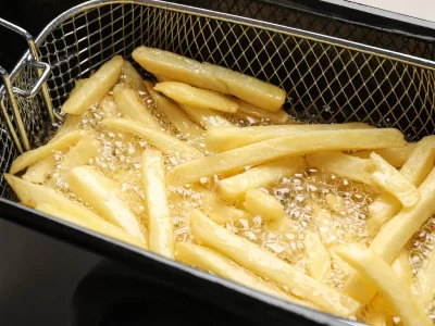 Cooking delicious french fries in hot oil, closeup